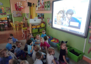 Grupa dzieci ogląda na tablicy prezentację multimedialną o prawach dziecka